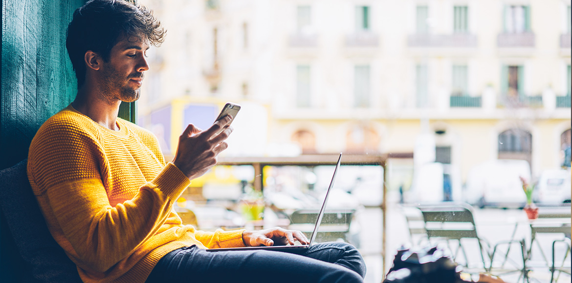 Man in yellow on his phone and laptop